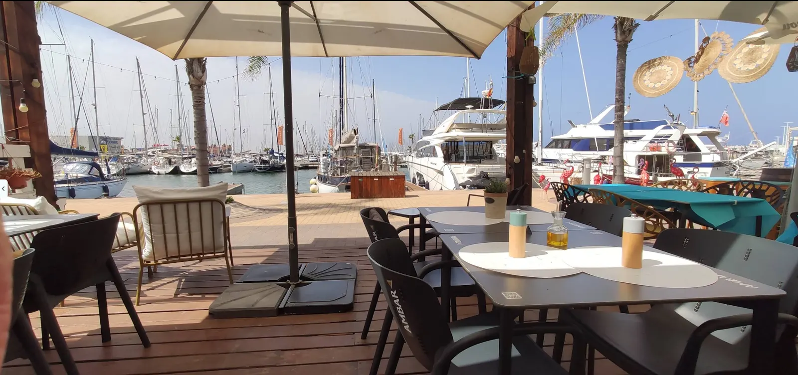 Terraza de A.mar Café Restaurante frente al puerto deportivo con mesas y veleros
